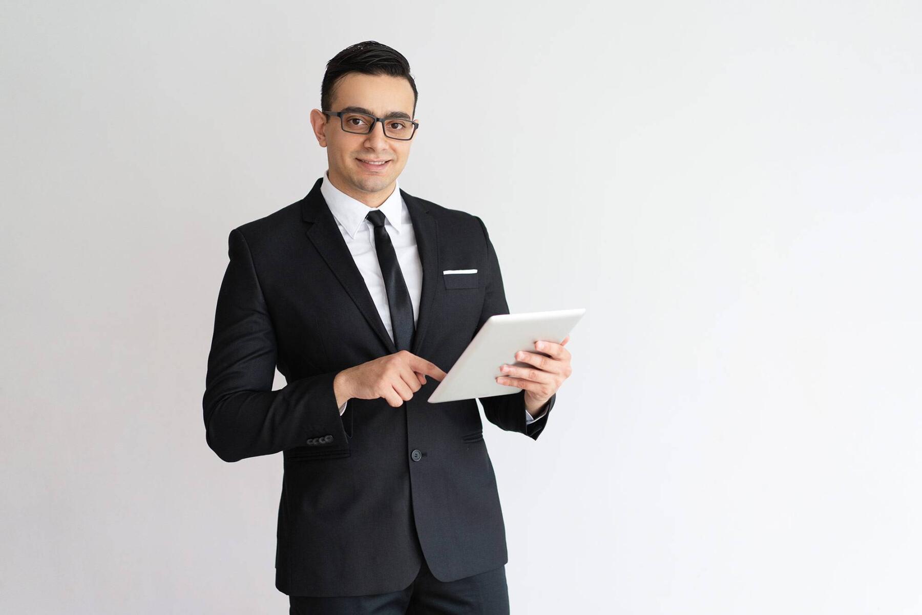 cheerful-young-businessman-checking-email-tablet-looking-camera